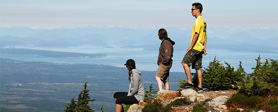 3 people standing near a cliff on Mount Washington looking at the view